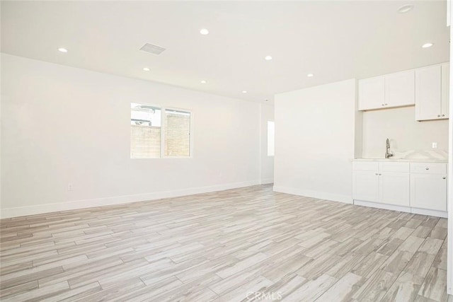 unfurnished room with sink and light hardwood / wood-style floors