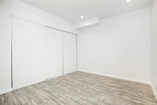 unfurnished bedroom featuring light wood-type flooring and a closet