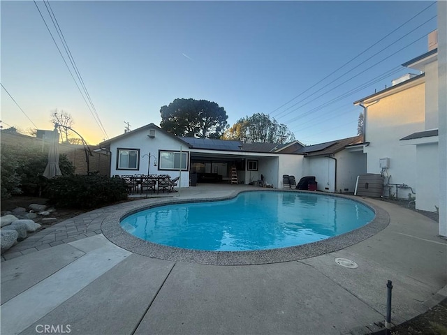 pool at dusk featuring a patio area