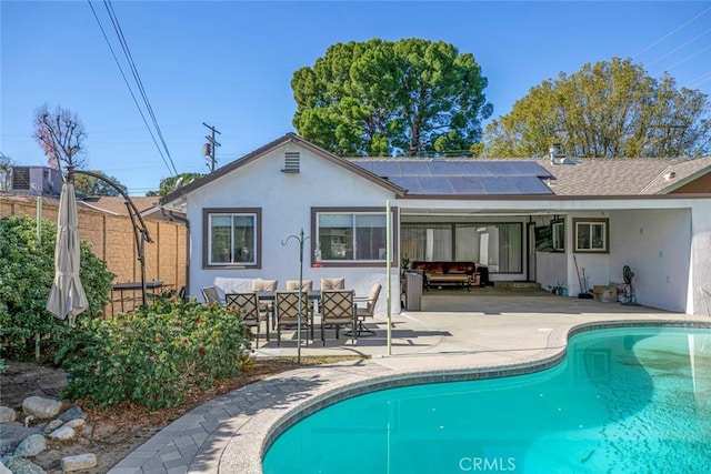 rear view of house featuring a fenced in pool, a patio, and solar panels