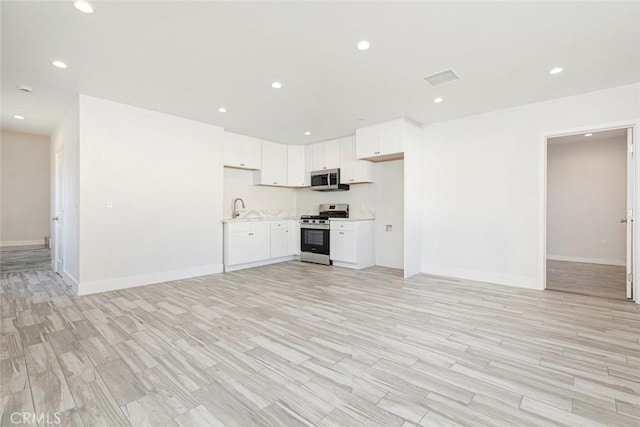 unfurnished living room featuring sink and light wood-type flooring