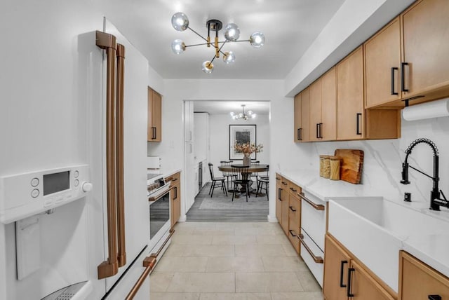 kitchen with sink, hanging light fixtures, a notable chandelier, light stone countertops, and stove