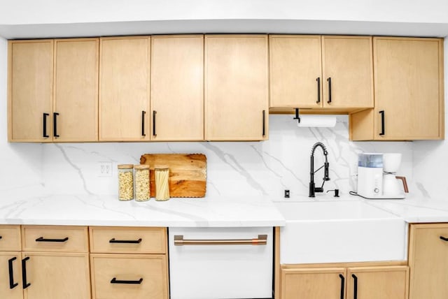 kitchen featuring light stone countertops, sink, light brown cabinetry, and decorative backsplash