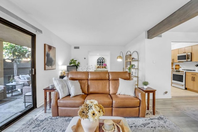 living room featuring beamed ceiling and light hardwood / wood-style floors