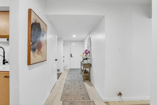 corridor featuring light tile patterned floors and sink