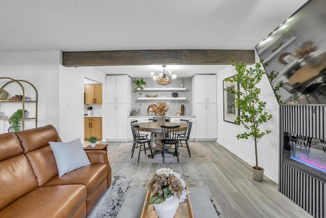 living room with beamed ceiling, a chandelier, and light wood-type flooring