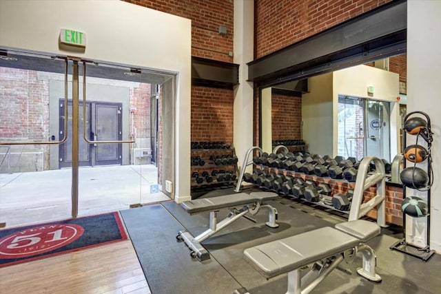 exercise room featuring a high ceiling and brick wall