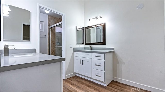 bathroom with hardwood / wood-style flooring, walk in shower, and vanity