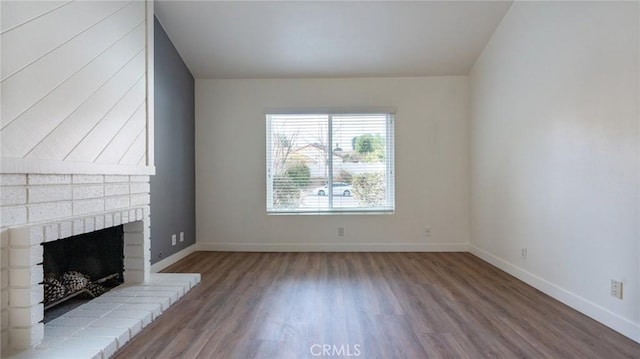 unfurnished living room with hardwood / wood-style flooring and a brick fireplace