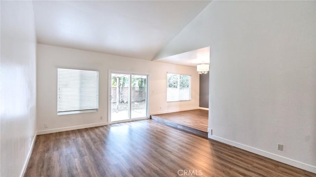 empty room featuring an inviting chandelier, dark hardwood / wood-style flooring, and lofted ceiling