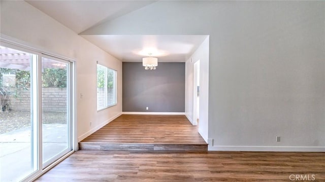 unfurnished dining area with hardwood / wood-style flooring, an inviting chandelier, and vaulted ceiling