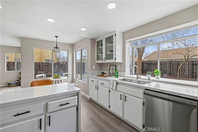 kitchen with sink, dishwasher, white cabinetry, dark hardwood / wood-style floors, and decorative light fixtures