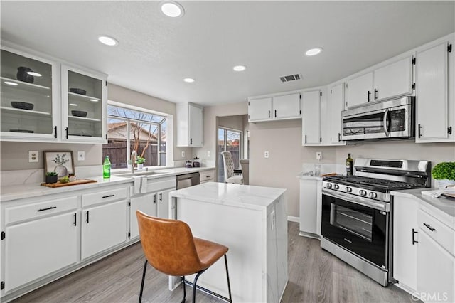 kitchen featuring a kitchen island, sink, white cabinets, light hardwood / wood-style floors, and stainless steel appliances