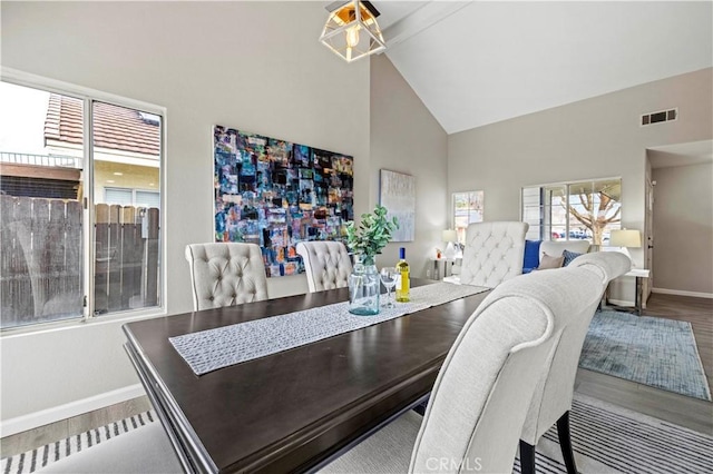 dining room with beam ceiling, hardwood / wood-style flooring, and high vaulted ceiling