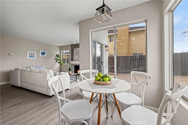 dining space with hardwood / wood-style flooring, a large fireplace, and a wealth of natural light