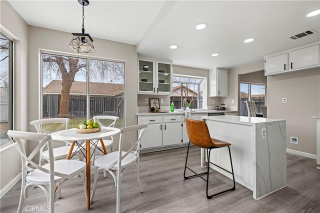 kitchen featuring hanging light fixtures, white cabinetry, a center island, and light hardwood / wood-style floors