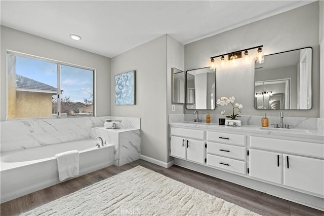 bathroom with vanity, wood-type flooring, and a tub to relax in