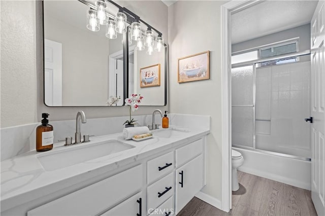 full bathroom with toilet, wood-type flooring, bath / shower combo with glass door, and vanity