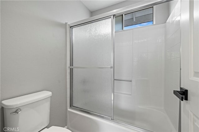 bathroom featuring toilet and shower / bath combination with glass door