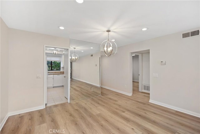 empty room featuring light hardwood / wood-style floors and a notable chandelier