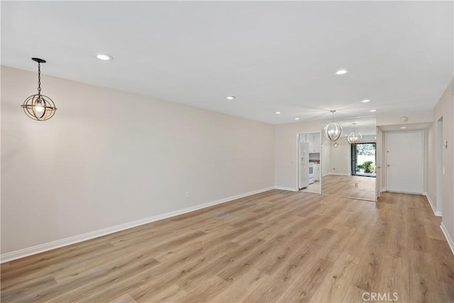 unfurnished living room featuring light hardwood / wood-style floors and an inviting chandelier