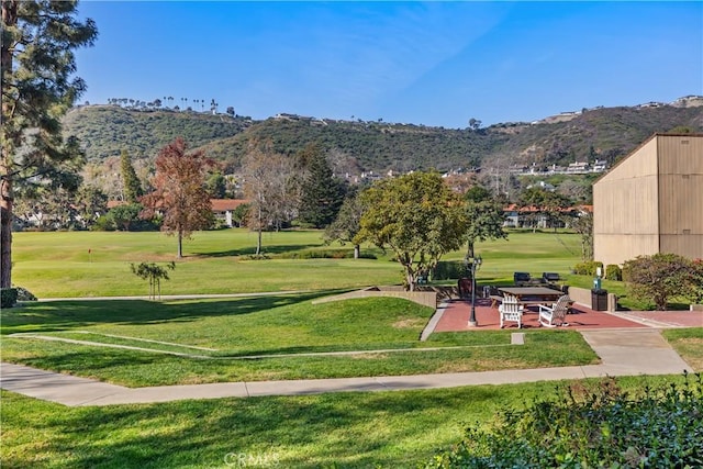 view of property's community featuring a mountain view, a lawn, and a patio