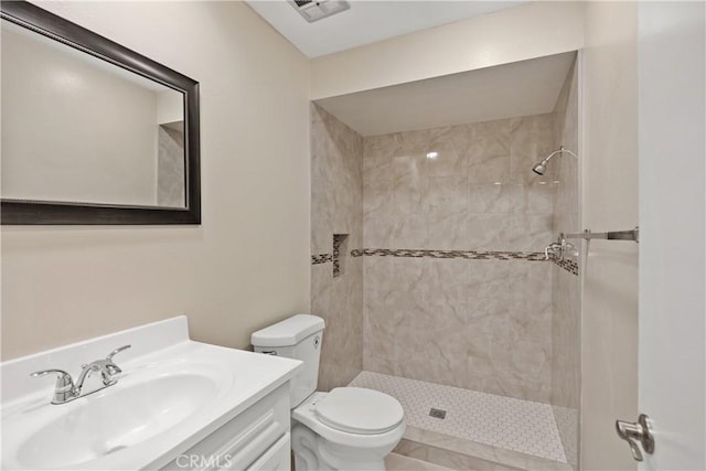 bathroom featuring vanity, toilet, and tiled shower