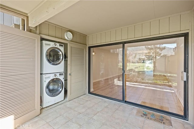 laundry room with stacked washer / dryer and wooden walls