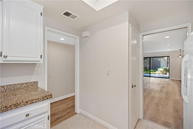 kitchen featuring light stone counters, white cabinetry, white refrigerator, and light tile patterned flooring