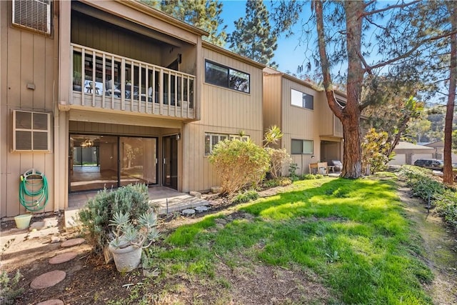 back of property with a balcony and a lawn