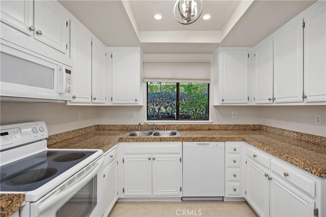 kitchen with white appliances, sink, white cabinets, a raised ceiling, and light tile patterned flooring