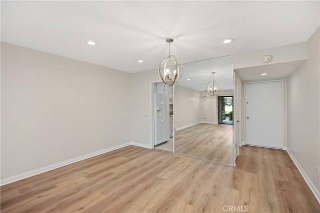 empty room with light wood-type flooring and a chandelier