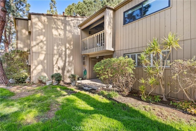 back of property featuring a balcony and a yard