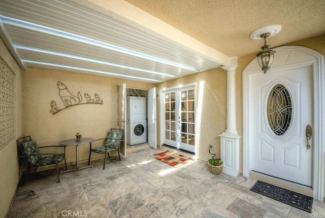 view of exterior entry with stacked washer and dryer and french doors