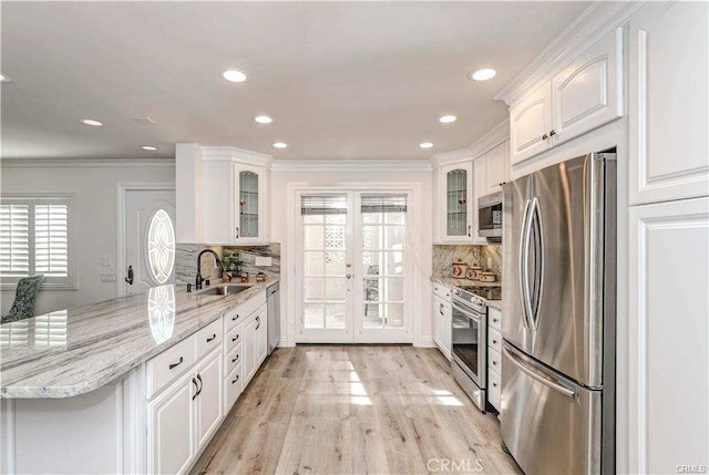 kitchen with sink, backsplash, white cabinetry, light stone countertops, and stainless steel appliances