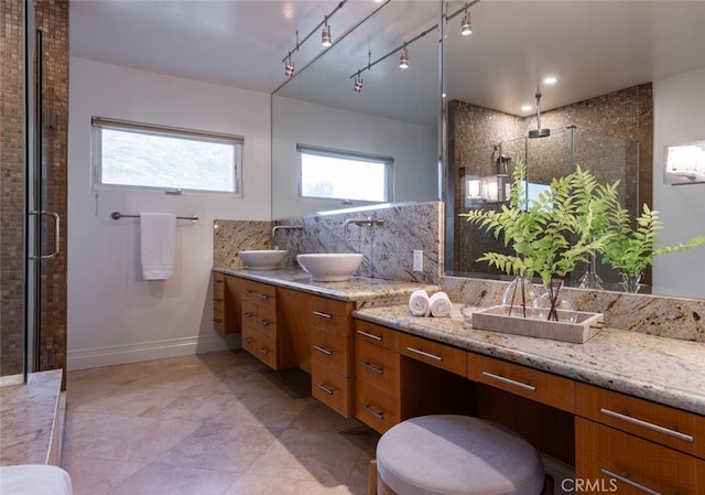 bathroom with vanity, a shower with door, and backsplash