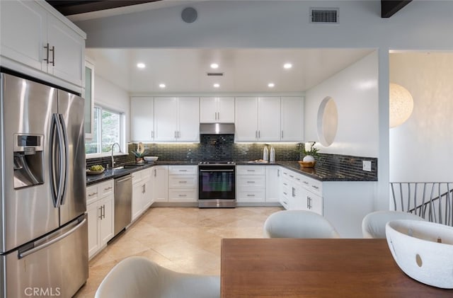 kitchen featuring sink, backsplash, stainless steel appliances, white cabinets, and vaulted ceiling