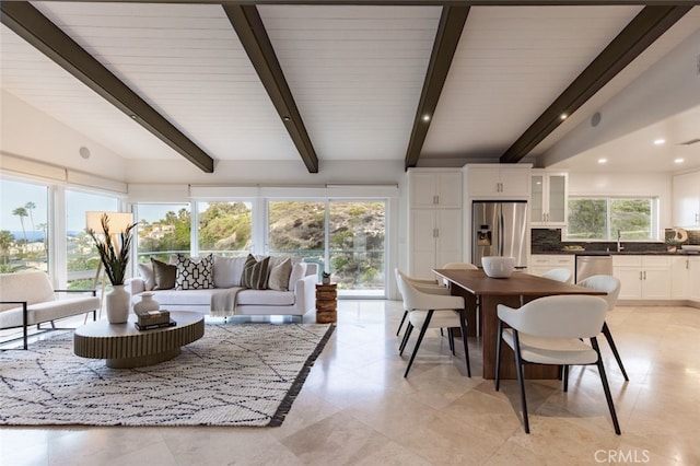 dining space with sink and lofted ceiling with beams