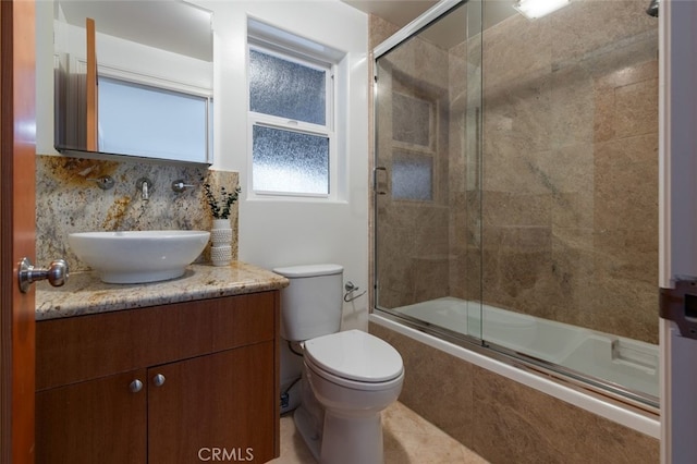 full bathroom featuring vanity, decorative backsplash, enclosed tub / shower combo, and toilet