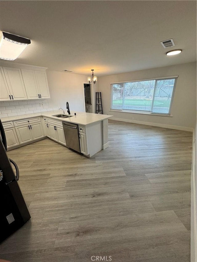 kitchen with visible vents, light wood finished floors, a peninsula, white cabinets, and dishwasher