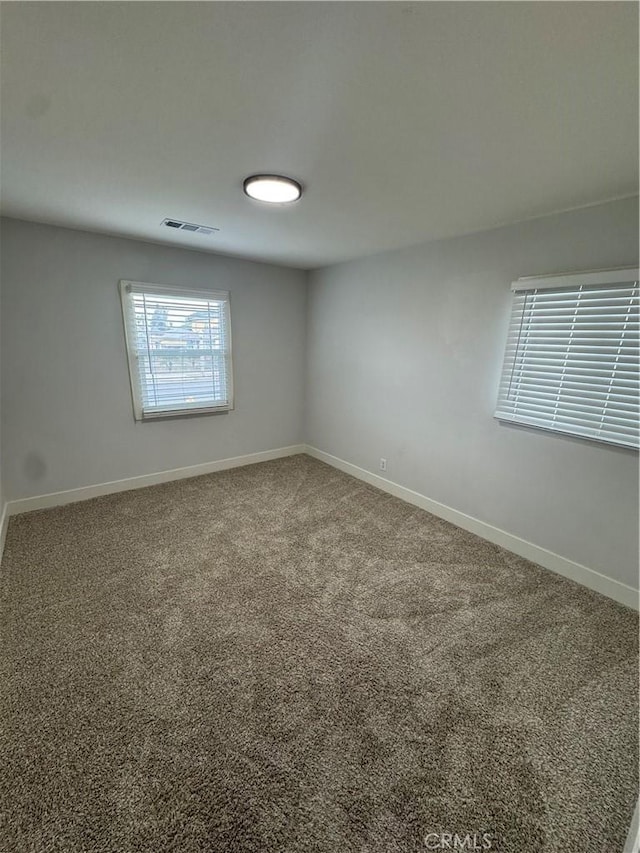 empty room featuring visible vents, baseboards, and carpet floors