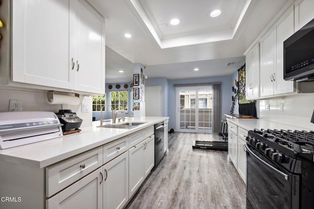 kitchen with sink, dishwashing machine, white cabinets, a tray ceiling, and gas stove