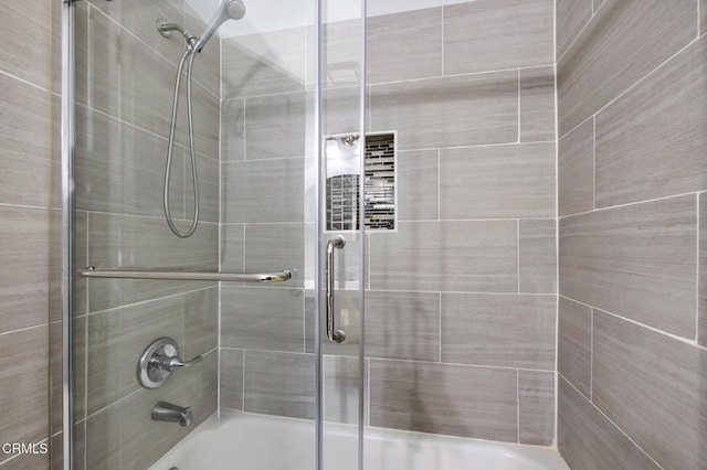 bathroom with combined bath / shower with glass door