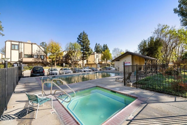 view of pool with a hot tub and a patio