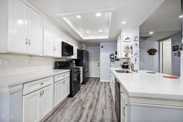 kitchen featuring black appliances, white cabinetry, sink, a raised ceiling, and light hardwood / wood-style flooring