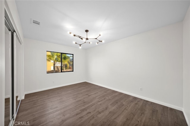 unfurnished bedroom with dark hardwood / wood-style flooring, a chandelier, and a closet