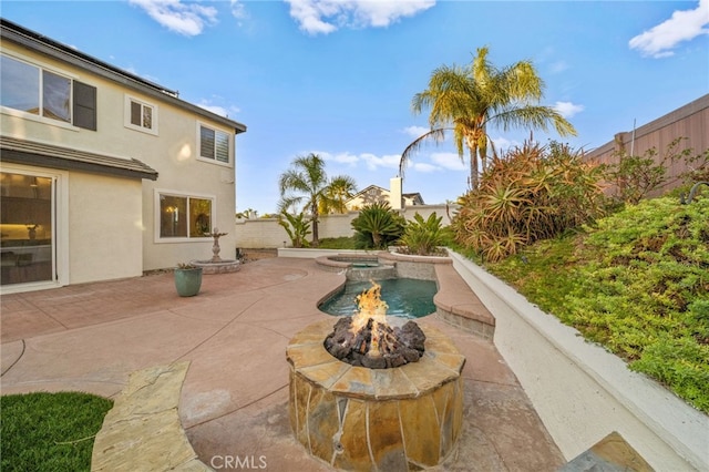 view of patio featuring an in ground hot tub and a fire pit