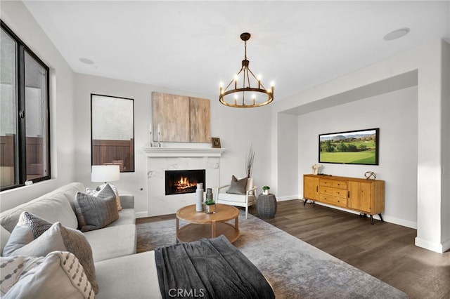 living room with an inviting chandelier, a fireplace, and dark wood-type flooring