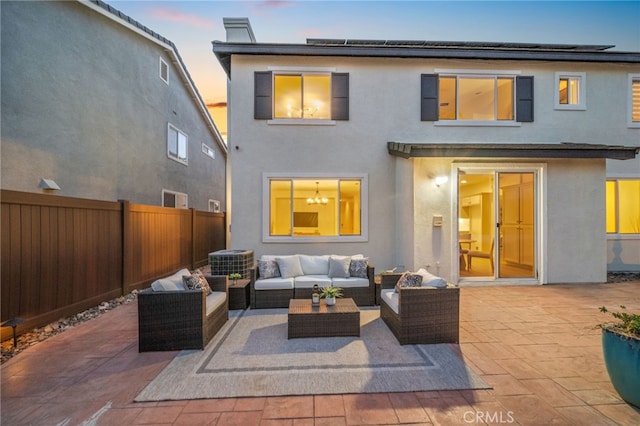 back house at dusk with an outdoor living space and a patio area