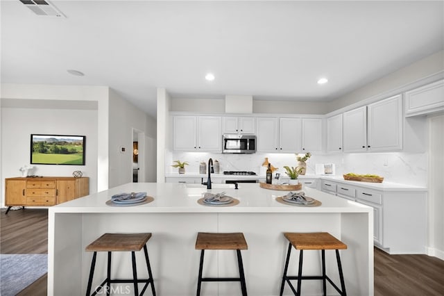 kitchen with white cabinetry, an island with sink, and a breakfast bar area